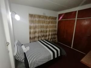 a small bedroom with a bed and a curtain at Overnight Stay in Johannesburg