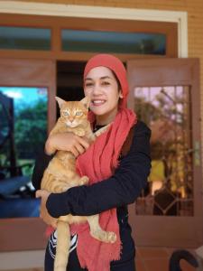 una mujer está sosteniendo un gato en sus brazos en Karma Traders Kampot, en Kampot