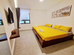 a bedroom with a bed with yellow sheets and a television at Aki 秋 Hostel in Da Lat