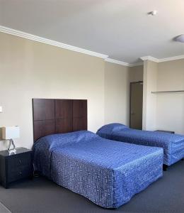 2 Betten in einem Hotelzimmer mit blauer Bettwäsche in der Unterkunft The Bexley Motel in Sydney