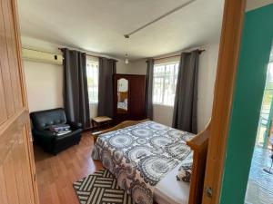 a bedroom with a bed and a chair at Green Bay Villa in Pereybere