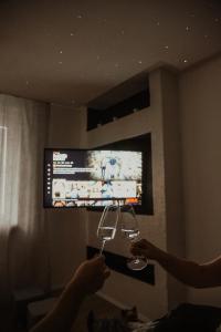 two people holding wine glasses in front of a tv at Apartman PENNY in Zvolen