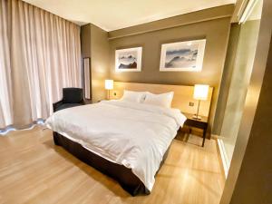 1 dormitorio con 1 cama blanca grande y 2 lámparas en Straits Suite by C Homestay Malacca en Melaka