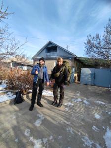 two men standing in front of a house in the snow at Kurjun in Karakol