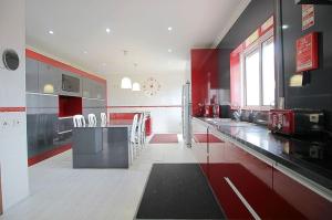 エシュポゼンデにあるCasa com piscina para 10 pessoas - 5 min da praia Esposendeの赤と白のキッチン(テーブル、椅子付)