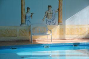 einen Stuhl neben einem Pool mit einem Gemälde in der Unterkunft Exklusives Ferienhaus mit Schwimmbad und Sauna in Grömitz