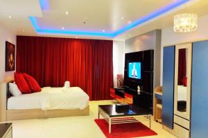 パトンビーチにあるBest 2 bedroom Apartment 2min walk to Patong Beachのベッドルーム(赤いカーテン付きのベッド、テレビ付)