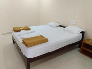 a bedroom with a white bed with two brown pillows at ORANGE SKY INN HOLIDAY HOME in Canacona