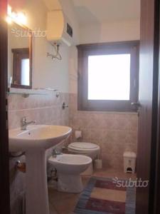 ein Bad mit einem Waschbecken, einem WC und einem Fenster in der Unterkunft MAKARI, Villetta Rocca Pirciata in Macari