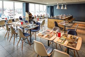 un restaurant avec des tables et des chaises ainsi qu'un bar dans l'établissement ibis London Heathrow Airport, à Hillingdon