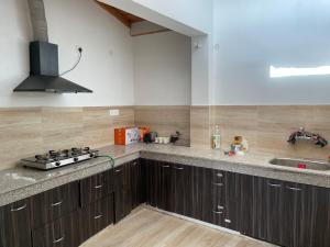 a kitchen with wooden cabinets and a sink and a stove at KAFAL TREE Home Stay - PET FRIENDLY in Bhowāli