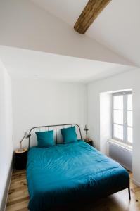 a bedroom with a bed with blue sheets and a window at Gîte Ohlavache! in Champtoceaux