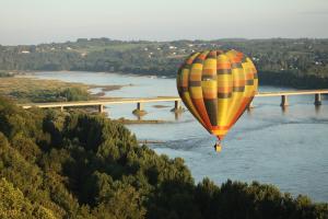 een heteluchtballon die over een rivier vliegt met een brug bij Gîte Ohlavache! in Champtoceaux