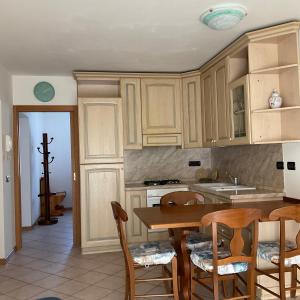 uma cozinha com armários de madeira e uma mesa e cadeiras em Casa Stefani em Commezzadura