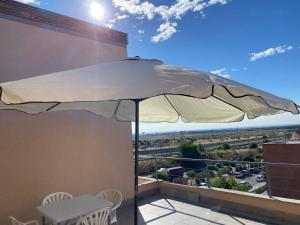un ombrellone bianco su un balcone con tavolo e sedie di Apartamento de 1 dormitorio, Ático 4PAX ad Alcorcón