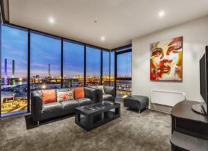 a living room with a couch and large windows at Lovely waterfront condo with swimming pool and gym in the heart of Docklands in Melbourne