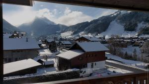 a view of a town with snow covered buildings and mountains at Appartement ensoleillé in Morzine