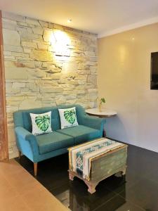 a living room with a blue couch and a stone wall at WARISAN Heritage Boutique Hotel in Solo