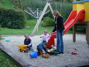 Eine Frau und drei Kinder spielen auf einem Spielplatz in der Unterkunft Buchgrabenhof in Windisch Minihof