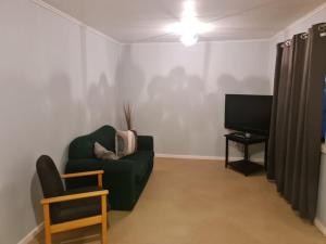 a living room with a green couch and a television at City Centre Apartments in Coober Pedy