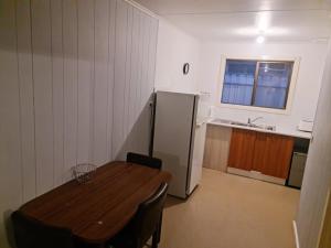 a kitchen with a wooden table and a refrigerator at City Centre Apartments in Coober Pedy