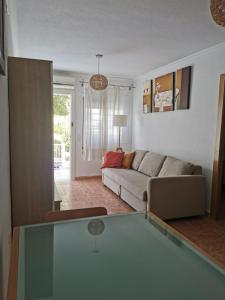 un soggiorno con divano e tavolo in vetro di Apartamento totalmente equipado con jardín y WiFi Santa Pola Gran Alacant a Gran Alacant