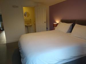 a bedroom with a large white bed and a sink at Garden Apartment in Didcot