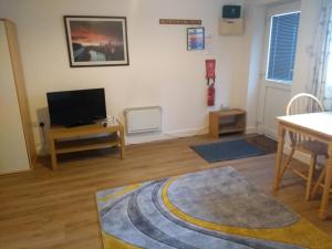 a living room with a television and a table at Garden Apartment in Didcot