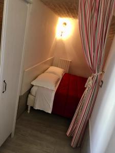 a small bed in a small room with a curtain at L’arquele in Noci