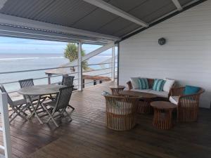 eine Veranda mit einem Sofa, einem Tisch und Stühlen in der Unterkunft vert lagon in Saint-Pierre