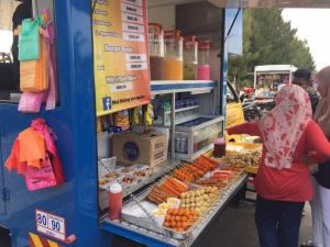 une femme debout devant un stand de nourriture dans l'établissement MELAKA BEACH VILLA ( A TYPE ), à Kelebang Besar
