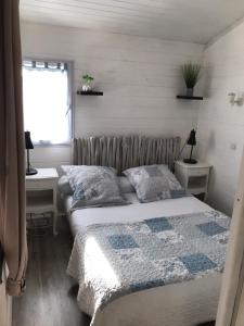 1 dormitorio con 1 cama, 2 mesas y una ventana en La cabane et sa cascade, en Lège-Cap-Ferret