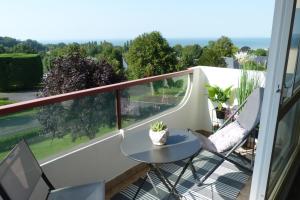 een balkon met een tafel en stoelen en een raam bij Studio vue panoramique sur mer in Villers-sur-Mer