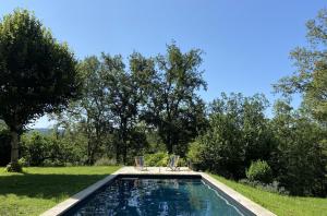 a swimming pool in a yard with two chairs at Maison d’hôte Les Grands Chênes in Valojoulx