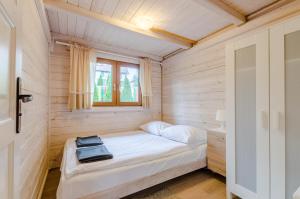 - un petit lit dans une chambre avec fenêtre dans l'établissement Kaszubski Zakątek, à Wdzydze Tucholskie
