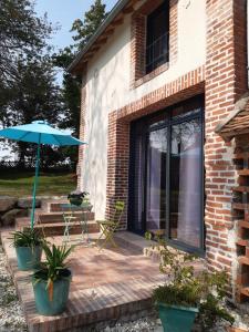 een patio met een parasol en een tafel en stoelen bij TUILERIE DE LA COTE 4* in Ouzouer-sur-Trézée