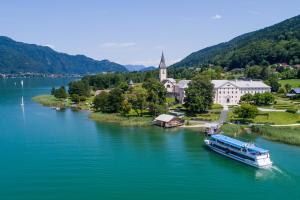 a boat on a river in front of a town at Gasthof Zur Post in Ossiach