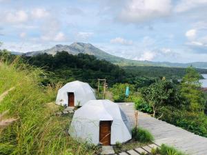 two tents in a field with a mountain in the background at Kubah Bali Glamping in Kintamani