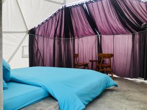 Bett in einem Zelt mit einem Tisch und Stühlen in der Unterkunft Kubah Bali Glamping in Kintamani