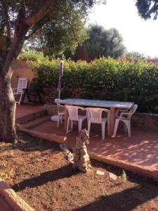 un orsacchiotto seduto accanto a un tavolo e sedie di Villa Chiara Villetta con giardino IUN 4807 a Porto Pollo