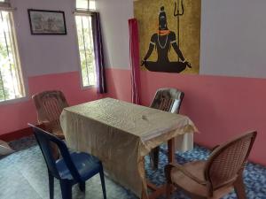 una mesa y sillas en una habitación con una pintura en Johnson's Homestay - Ecohouseboat, en Alleppey