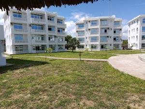 un grand immeuble d'appartements blanc avec un parc en face dans l'établissement HavenHouse Kijani - 1 Bedroom Beach Apartment with Swimming Pool, à Malindi