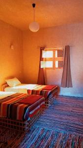 Cette chambre comprend 2 lits et une fenêtre. dans l'établissement Aghurmi Siwa Ecolodge & Salt Cave, à Siwa