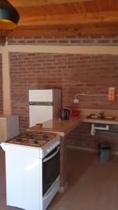 cocina con estufa blanca y pared de ladrillo en Cabaña Solares en La Silleta