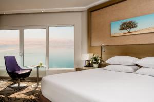 a bedroom with a large bed and a large window at Vert Dead Sea Hotel in Ein Bokek