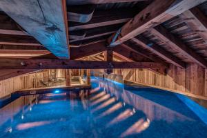 an indoor swimming pool with wooden ceilings and blue water at HOTEL LE VAL D'ISERE in Val dʼIsère