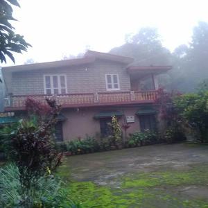 a house with a balcony on top of it at Hill side estate in Madikeri