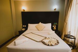 Panone Hotels - King'ori Kilimanjaro Airport في موشي: غرفة نوم مع سرير أبيض كبير مع اللوح الأمامي كبير