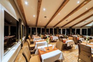 a restaurant with white tables and chairs and windows at Seehotel Heidehof in Klein Nemerow