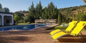 une chaise jaune assise à côté de la piscine dans l'établissement Quinta da Cortiça, à São Brás de Alportel